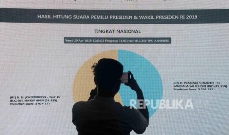 Jurnalis mengambil gambar pada layar perolehan suara sementara di Pusat Informasi Penghitungan Suara dan Rekapitulasi Hasil Penghitungan Perolehan Suara Pemilihan Umum Tahun 2019 di Kantor KPU, Jakarta, Sabtu (20/4).