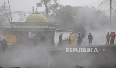  Tim penyelamat terlihat melalui asap dari material vulkanik panas dari letusan Gunung Semeru di desa Kajar Kuning, Lumajang, Jawa Timur, Indonesia, Senin, 5 Desember 2022. Kondisi cuaca yang membaik Senin memungkinkan penyelamat melanjutkan upaya evakuasi dan pencarian kemungkinan korban setelah gunung berapi tertinggi di pulau terpadat di Indonesia meletus, dipicu oleh hujan monsun.