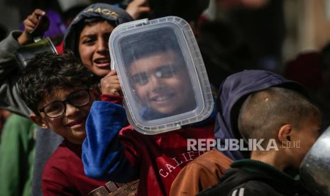 Anak-anak pengungsi Palestina antre untuk menerima makanan yang disediakan oleh relawan di kota Deir Al Balah, Jalur Gaza Selatan.