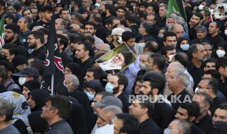 Seorang demonstran pro-pemerintah Iran mengangkat poster Pemimpin Tertinggi Ayatollah Ali Khamenei selama rapat umum mengutuk protes anti-pemerintah baru-baru ini atas kematian Mahsa Amini, seorang wanita berusia 22 tahun yang telah ditahan oleh polisi moral negara, di Teheran, Iran, Minggu, 25 September 2022.