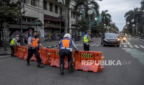 Petugas gabungan memasang water barrier saat penutupan jalan di Jalan Asia Afrika, Kota Bandung, Ahad (13/2/2022). Pemerintah Kota Bandung kembali menerapkan kebijakan buka tutup di tiga titik ruas jalan dari pukul pukul 18.00 WIB hingga 24.00 WIB pada akhir pekan. Penutupan ruas jalan tersebut sebagai langkah antisipasi terhadap lonjakan Covid-19 di Kota Bandung. 