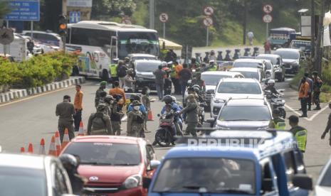 Petugas gabungan mengarahkan kendaraan saat penerapan ganjil genap di Jalan Raya Puncak, Gadog, Kabupaten Bogor, Jawa Barat, Jumat (3/9). Pemerintah Kabupaten Bogor menerapkan uji coba sistem ganjil genap bagi kendaraan di wilayah puncak pada tanggal 3 hingga 5 September 2021, jika uji coba tersebut efektif mengurai kepadatan akan dilanjutkan terus setiap akhir pekan. Republika/Putra M. Akbar