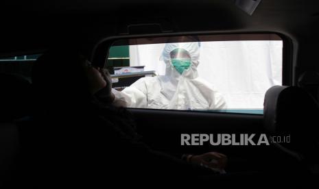 Petugas kesehatan melakukan rapid test antigen kepada calon penumpang secara drive thru