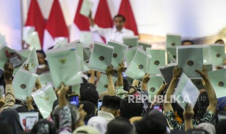 Warga menunjukkan sertifikat tanah yang telah diserahkan pemerintah saat Presiden Joko Widodo memberikan sambutan pada penyerahan sertifikat tanah di Bandung, Jawa Barat, Sabtu (3/2/2024). Presiden menyerahkan 3.000 sertifikat hak milik (SHM) atas tanah hasil program pendaftaran tanah sistematis lengkap (PTSL) kepada masyarakat di Kabupaten Bandung, Jawa Barat.  