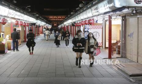  Pengunjung mengenakan masker pelindung untuk membantu mengekang penyebaran virus corona berjalan-jalan di Kuil Sensoji di distrik Asakusa di Tokyo, pada Selasa, 30 November 2021. Perdana Menteri Jepang Fumio Kishida pada Kamis mengatakan negaranya akan melonggarkan aturan pengendalian COVID-19 di perbatasan bulan depan.