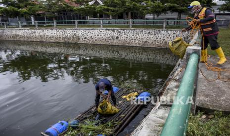 Petugas membersihkan sampah di Kolam Retensi