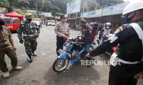 Petugas gabungan menghentikan pengendara sepeda motor yang diduga akan mudik di titik pemeriksaan perbatasan Cianjur - Bogor, Jalan Raya Puncak, Kabupaten Cianjur, Jawa Barat