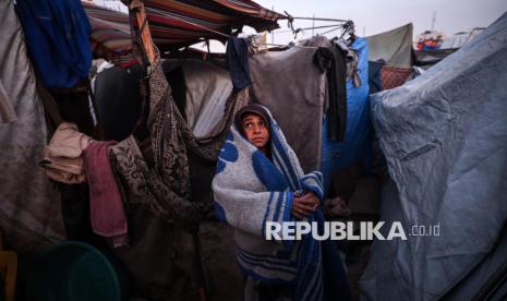 Anak Gaza berdiri di depan tenda pengungsian yang terbuat dari potongan kain dan nilon, di sebuah kamp pengungsi Palestina di tepi pantai di Deir al-Balah, Jalur Gaza tengah, Jumat (27/12/2024). Anak-anak Gaza yang tinggal di dalam tenda pengungsian hidup dengan penuh keterbatasan. Mereka harus menghadapi ancaman hawa dingin dan keterbatasan pasokan makanan. Tenda-tenda yang dibangun seadanya tidak melindungi mereka sepenuhnya dari hawa dingin. Agresi Israel ke Palestina telah membuat 90 persen warga Gaza mengungsi dan tinggal di kamp pengungsian.