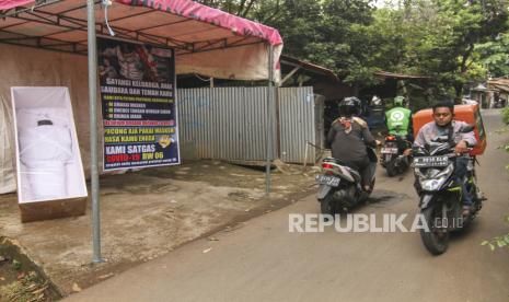 Sejumlah pengendara yang tidak menggunakan masker melintas di depan instalasi berisi imbauan protokol kesehatan di Jalan Jambu, Beji, Depok, Jawa Barat, Rabu (23/9/2020). Warga setempat berinisiatif untuk memasang peti mati berisi replika jenazah untuk mengingatkan masyarakat agar tetap mematuhi protokol kesehatan sebagai upaya menekan penyebaran COVID-19.