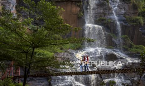 Sejumlah pengunjung berfoto di kawasan Wisata Curug Batu Templek, Cisanggarung Lebak, Kabupaten Bandung, Jawa Barat, Ahad (14/5/2023). Kawasan wisata yang memiliki lanskap alam air terjun yang terbentuk akibat pelapukan batu selama jutaan tahun tersebut ramai dikunjungi wisatawan pada akhir pekan.