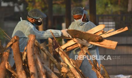 Anggota keluarga yang mengenakan Alat Pelindung Diri (APD) mempersiapkan tumpukan kayu pemakaman dan upacara terakhir di tempat kremasi untuk korban COVID-19 di New Delhi, India, 10 Mei 2021. Seruan untuk penutupan secara nasional telah meningkat seiring dengan jumlah COVID baru -19 infeksi dan kematian terkait berdiri mendekati rekor tertinggi pada 10 Mei.