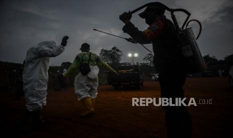 Petugas menyemprotkan cairan disinfektan saat prosesi memakamkan jenazah Covid-19  (ilustrasi)