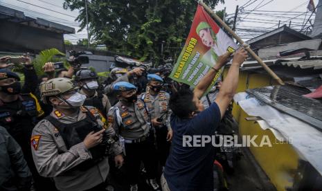 Sejumlah anggota kepolisian mengimbau warga untuk mencabut bendera bergambar Imam Besar FPI Habib Rizieq Shihab di Jalan Petamburan III, Jakarta, Rabu (30/12). Aparat gabungan dari TNI dan Polri mendatangi kawasan Petamburan III untuk mencabut sejumlah atribut FPI pasca pembubaran organisasi tersebut oleh pemerintah. Republika/Putra M. Akbar