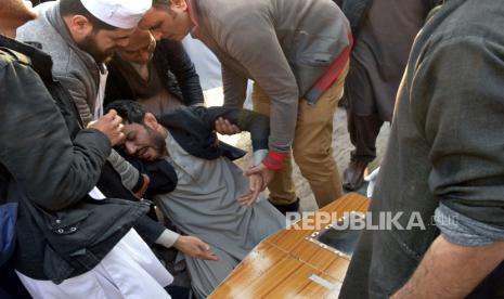 Seorang pria menangis di samping peti mati anggota keluarganya yang tewas dalam serangan bom bunuh diri di dalam sebuah masjid, di sebuah rumah sakit, Peshawar, Pakistan, Senin, (30/1/2023). 