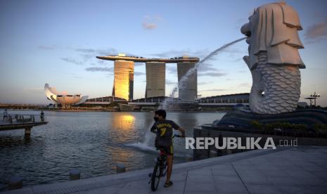 Seorang anak yang mengenakan masker di patung Merlion, Taman Merlion, Singapura, Rabu (15/4). Singapura pada 14 April mewajibkan semua orang untuk mengenakan maker di luar rumah