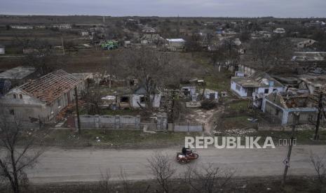 Seorang pria mengendarai sepeda motor di depan rumah-rumah yang telah hancur selama pertempuran antara pasukan Rusia dan Ukraina di kota Arhanhelske, Ukraina, yang baru saja dibebaskan, Senin, 5 Desember 2022. Menteri Keuangan Amerika Serikat (AS) Janet Yellen mengisyaratkan bahwa, pemerintahan Presiden Joe Biden siap memberikan bantuan kepada Ukraina secara berkelanjutan untuk memerangi invasi Rusia. 