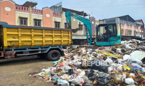 Warga melintas di depan TPS Pasar Kidul, Kecamatan Cihideung, Kota Tasikmalaya, Jumat (27/1/2023). Sampah di TPS itu mengalami penumpukan hingga hampir meluap ke jalan. 