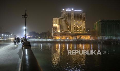 Mesir Majukan Jam Malam Empat Jam Saat Idul Fitri. Sepasang suami istri berjalan di Jembatan Kasr El Nile dekat hotel yang terang memperlihatkan hati untuk wabah corona di Kairo, Mesir.