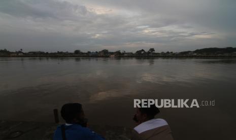 Dua warga duduk di tepian Sungai Kapuas seusai hujan reda di Pontianak, Kalimantan Barat, Selasa (13/4/2021). BMKG menghimbau masyarakat Kalimantan Barat untuk mewaspadai potensi cuaca ekstrem berupa hujan sedang hingga lebat yang dapat disertai petir dan angin kencang berdurasi singkat pada 12 April hingga 17 April 2021. 