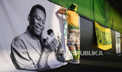  Seorang penggemar memperlihatkan tanda mendukung Pele di pesta penggemar Brasil sebelum pertandingan sepak bola babak 16 besar Piala Dunia antara Brasil dan Korea Selatan. Pele merupakan Legenda sepak bola Brasil yang memenangkan rekor tiga Piala Dunia dan menjadi salah satu tokoh olahraga paling berpengaruh abad lalu meninggal, Jumat (30/12). Sosok berusia 82 tahun itu adalah pembawa standar 'permainan cantik' itu telah menjalani perawatan kanker usus besar sejak 2021.