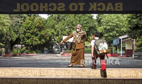 Seorang guru memberikan arahan jalur pulang kepada siswa setelah  Pembelajaran Tatap Muka (PTM) di SDN Anyelir 1, Depok, Jawa Barat, Selasa (28/9/2021). Pemerintah Kota Depok melakukan uji coba sejumlah Sekolah Dasar (SD) untuk melaksanakan Pembelajaran Tatap Muka Terbatas (PTMT) dengan menerapkan 50 persen siswa dan menerapkan protokol kesehatan untuk evaluasi sebelum memberikan izin seluruh sekolah pada tanggal 4 Oktober 2021. 