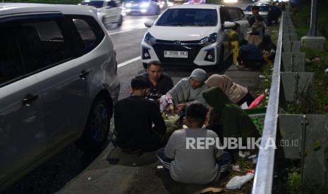 Sejumlah pemudik menyantap makanan saat berbuka puasa di badan jalan Tol Cikopo-Palimanan (Cipali), Majalengka, Jawa Barat, Rabu (19/4/2023). Astra Tol Cipali memproyeksikan puncak arus balik Lebaran Idul Fitri 2023 di Tol Cipali akan terjadi pada Rabu, 26 Maret 2023.