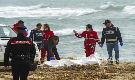  Relawan Palang Merah Italia dan penjaga pantai menemukan mayat setelah kapal migran pecah di laut yang ganas, di pantai dekat Cutro, Italia selatan, Ahad ( 26/2/2023). Petugas penyelamat mengatakan jumlah migran yang belum ditentukan telah meninggal dan puluhan lainnya telah meninggal diselamatkan setelah perahu mereka pecah di lepas pantai Italia selatan.