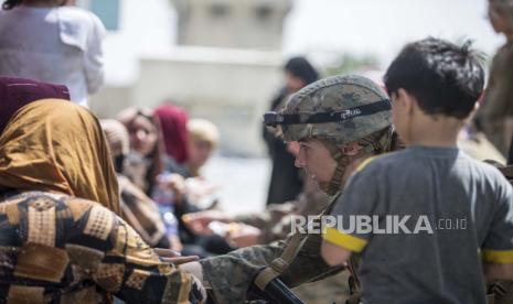 Masjid di AS Kumpulkan Donasi untuk Pengungsi Afghanistan. Dalam gambar yang disediakan oleh Korps Marinir AS, seorang anggota korps dengan Unit Ekspedisi Marinir (MEU) ke-24 memeriksa kesejahteraan para pengungsi selama evakuasi di Bandara Internasional Hamid Karzai di Kabul, Afghanistan, Jumat, 20 Agustus 2021.