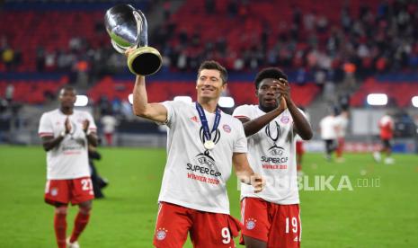 Pemain Bayern Munchen Robert LEWANDOWSKI (kiri) dan Alphonso Davies mengangkat trophy seusai menjuarai UEFA Super Cup 2020 di Puskas Arena, Jumat (25/9/2020). Bayern menjadi juara UEFA Super Cup setelah mengalahkan Sevilla dengan skor 2-1.