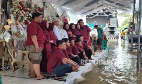 Sepasang pengantin di Desa Jagapura Kulon, Kecamatan Gegesik, Kabupaten Cirebon menggelar pernikahan di tengah kepungan banjir, Ahad (7/7/2024). 