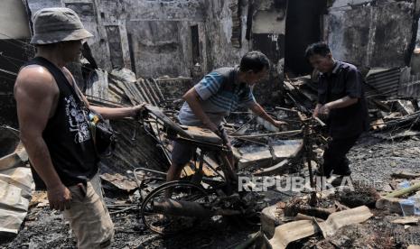 Warga mengevakuasi kendaraan motor yang terbakar di permukiman di kawasan Manggarai, Jakarta Selatan, Selasa (13/8/2024). Kemenag memberikan bantuan alat sholat dan mushola keliling untuk korban.