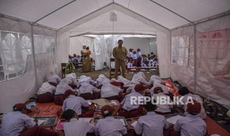 Sejumlah siswa mengikuti kegiatan belajar mengajar di tenda darurat saat hari pertama masuk sekolah di halaman SDN Citamiang, Jalan Loji, Pacet, Kabupaten Cianjur, Senin (9/1/2023). Sebanyak 262 siswa terpaksa belajar di tenda darurat pada hari pertama masuk sekolah karena bangunan sekolahnya terancam roboh akibat gempa bumi.