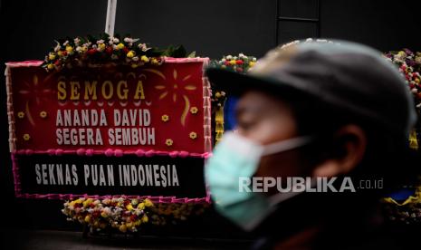 Warga berjalan di dekat karangan bunga dukungan untuk Cristalino David Ozora di Jakarta, Selasa (28/2/2023). Tim dokter mengungkapkan kesehatan David yang merupakan korban penganiayaan oleh anak mantan pejabat Ditjen Pajak, Mario Dandy Satrio, telah mengalami perkembangan signifikan namun masih perlu perawatan intensif dan observasi secara ketat.