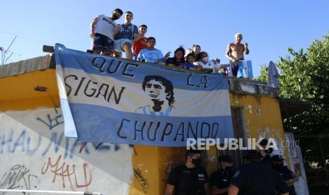  Fans berdiri di atas atap rumah di sepanjang iring-iringan mobil membawa Diego Maradona ke pemakaman Jardin de Bellavista di Buenos Aires, Argentina, Kamis, 26 November 2020. Pemain sepak bola hebat Argentina yang termasuk di antara pemain terbaik pernah dan yang memimpin negaranya meraih gelar Piala Dunia 1986 meninggal karena serangan jantung di rumahnya Rabu, pada usia 60.