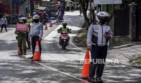 Petugas gabungan memegang spanduk imbauan protokol kesehatan saat operasi penyekatan dan pemeriksaan di perbatasan Kabupaten Bandung dengan Kota Bandung di Jalan Ir H Juanda, Kecamatan Cimenyan, Kabupaten Bandung, Ahad (7/2). Operasi penyekatan dan pemeriksaan bagi setiap kendaraan luar daerah yang masuk ke Kabupaten Bandung tersebut digelar dalam rangka Penerapan Pembatasan Kegiatan Masyarakat (PPKM) guna mencegah penyebaran Covid-19 di wilayah Kabupaten Bandung. Foto: Abdan Syakura/Republika