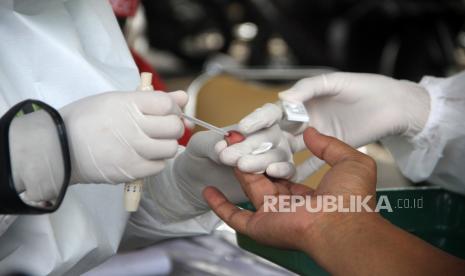 Petugas medis mengambil sampel darah pengguna kendaraan saat tes diagnostik cepat (rapid test) COVID-19 dengan sistem 