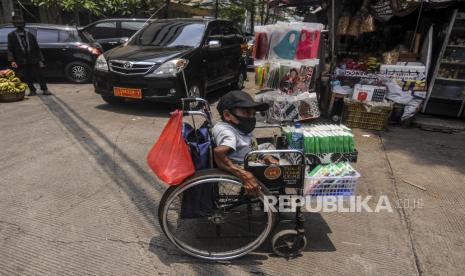 Penjual masker keliling  yang juga penyandang disabilitas Budi (39 tahun) membawa dagangannya menuju tempat berteduh di Jakarta, Sabtu, (17/10). 