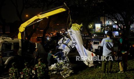 Kendaraan alat berat dibantu petugas gabungan mengangkut  puing-puing badan pesawat yang jatuh di Lapangan Sunburst Bumi Serpong Damai (BSD), Tangerang Selatan, Banten, Ahad (19/5/2024). Proses evakuasi tersebut dibantu menggunakan satu alat berat, satu mobil derek dan satu truk yang berlangsung selama sekitar 3 jam dari pukul 18.30 WIB hingga pukul 21.30 WIB. Komite Nasional Keselamatan Transportasi (KNKT) akan memindahkan puing-puing badan pesawat ke Bandara Pondok Cabe untuk dilakukan investigasi penyebab kecelakaan pesawat. Untuk diketahui, pesawat jenis Cessna 2006 dengan kode registrasi PK-IFP TECNAM milik Indonesia Flying Club terjatuh di Lapangan Sunburst BSD sekitar pukul 13.45 WIB yang menyebabkan tiga orang meninggal dunia yakni satu orang penerbang, satu orang teknisi dan satu orang penumpang.