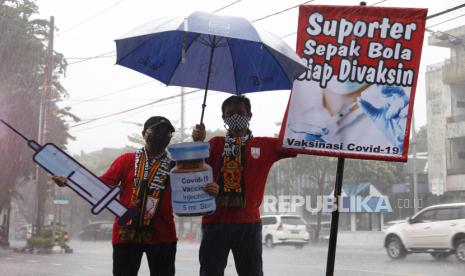 Suporter sepakbola Pasoepati mengusung poster bertuliskan Suporter Sepak Bola Siap Divaksin saat aksi di kawasan Ngarsopuro, Solo, Jawa Tengah, Selasa (5/1/2021). Aksi tersebut sebagai wujud dukungan kepada pemerintah untuk pelaksanaan vaksinasi COVID-19 guna memutus rantai penyebaran virus COVID-19. 