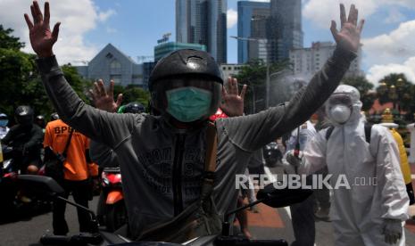 Petugas Badan Penanggulangan Bencana Daerah (BPBD) Jatim menyemprotkan cairan disinfektan ke pengendara motor di Surabaya, Jawa Timur, ahad (22/3/2020). 