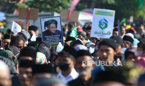 Sejumlah peserta membawa poster saat mengikuti Jalan Sehat Santri Sarungan yang diselenggarakan Nahdlatul Ulama di Kota Kediri, Jawa Timur, Minggu (30/10/2022). Jalan sehat mengenakan sarung dengan menyediakan sepuluh ribu lembar kupon undian berhadian dan diikuti oleh ribuan peserta tersebut sebagai puncak peringatan Hari Santri Nasional. 