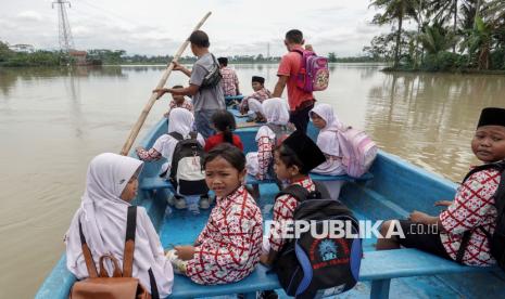 Sejumlah pelajar melewati banjir menggunakan perahu saat kembali ke rumah mereka di Desa Gentasari, Kroya, Cilacap, Jawa Tengah, Rabu (4/12/2024). Luapan air Sungai Tipar itu merendam 12 RT di Desa Gentasari serta memutus beberapa akses jalan sehingga aktivitas warga terpaksa menggunakan perahu yang disediakan desa. 