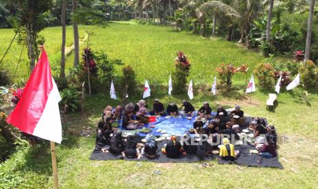 Warga Suku Osing makan bersama saat menggelar tradisi Mocoan Lontar di Pesinauan Desa Adat Kemiren, Banyuwangi, Jawa Timur, Selasa (17/8/2021). Mocoan Lontar Hadis Dagang itu merupakan tradisi selamatan sawah dan ladang dengan sajian makanan tradisional khas masyarakat  Osing 