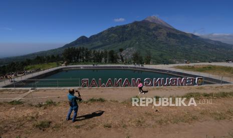 Pengunjung berfoto dengan latar belakang pemandangan Gunung Merapi.