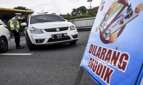 Petugas kepolisian mengarahkan kendaraan untuk memutar balik di pos pemeriksaan Pembatasan Sosial Berskala Besar (PSBB) di Gerbang Tol Cileunyi, Kabupaten Bandung, Selasa (28/4). Penindakan berupa pemeriksaan surat kendaraan, surat tugas serta mengarahkan kendaraan untuk memutar balik tersebut merupakan tidak lanjut kebijakan larangan penggunaan kendaraan umum dan kendaraan bermotor pribadi untuk mudik