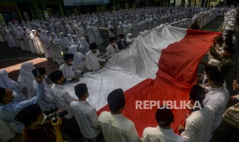 Sejumlah santri saat membentangkan bendera Merah Putih di Pondok Pesantren Asshiddiqiyah, Kebon Jeruk, Jakarta, Jumat (22/10). Bendera Merah Putih sepanjang 200 meter tersebut dibentangkan mengelilingi lapangan Pondok Pesantren Asshiddiqiyah dalam rangka memeriahkan Hari Santri Nasional 2021 yang bertemakan Santri Siaga Jiwa dan Raga. Republika/Putra M. Akbar