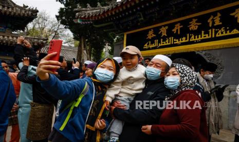 Sebuah keluarga berswafoto setelah sholat Idul Fitri di Masjid Niujie di Beijing, China, Sabtu (22/4/2023).