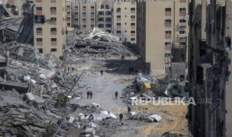 Warga berjalan di Puing Tower Hamad yang hancur dibom Israel di Khan Younis Selatan Gaza.  