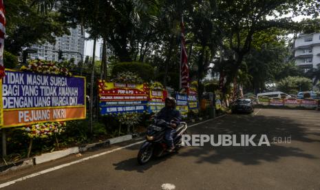 Pengendara motor melintas di dekat karangan bunga yang disimpan di Halaman Kantor DPRD DKI Jakarta, Kamis (2/9). Sebanyak 18 karangan bunga yang berisikan dukungan interpelasi terhadap Gubernur DKI Jakarta Anies Baswedan terkait gelaran Formula E. Republika/Putra M. Akbar