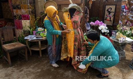 Penjaga stan menata kain produksi UMKM yang dipamerkan saat Gelar Potensi Kalurahan Budaya bertajuk Ruwat Bumi di Halaman Kantor Kalurahan Margoagung, Seyegan, Sleman, D. I Yogyakarta, Senin (31/10/2022). Acara yang digagas oleh Pemkab Sleman dan berlangsung hingga 1 November 2022 itu menampilkan berbagai potensi budaya serta UMKM dari 19 kalurahan yang berada di Kabupaten Sleman. 